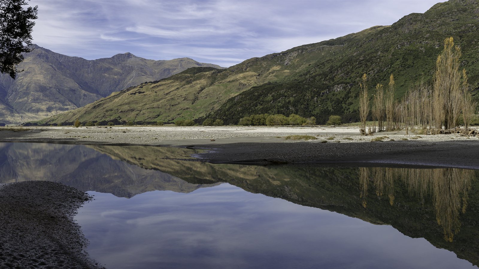 Braided river with wide gravel bars reflecting mountains